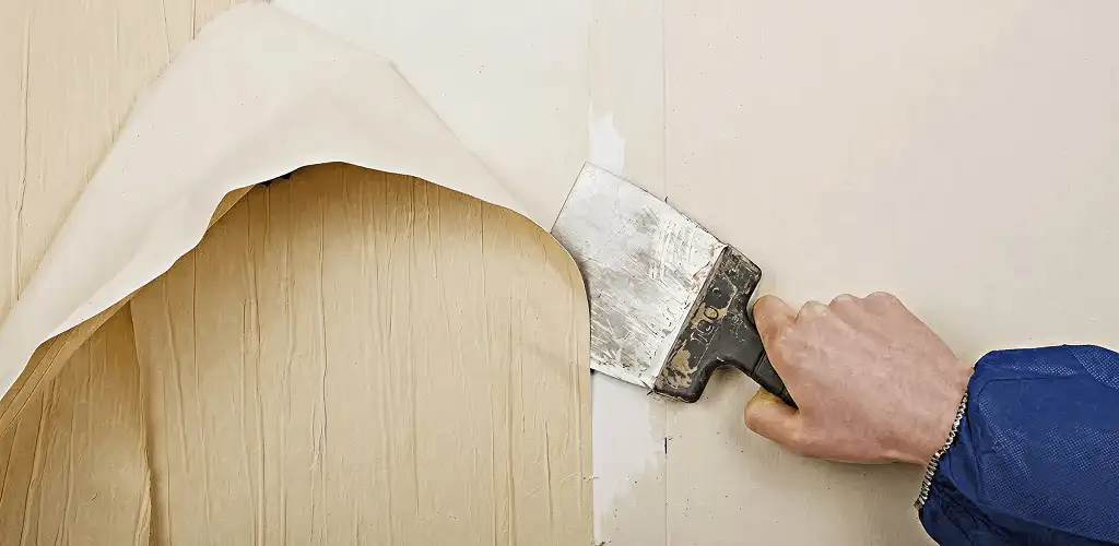 Handyman removing wallpaper with a scraper for wall preparation in Philadelphia, PA
