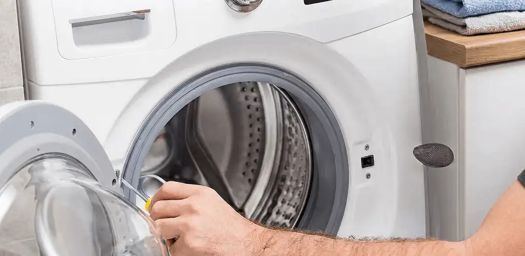 Handyman repairing a front-load washing machine and inspecting the drum in Philadelphia, PA
