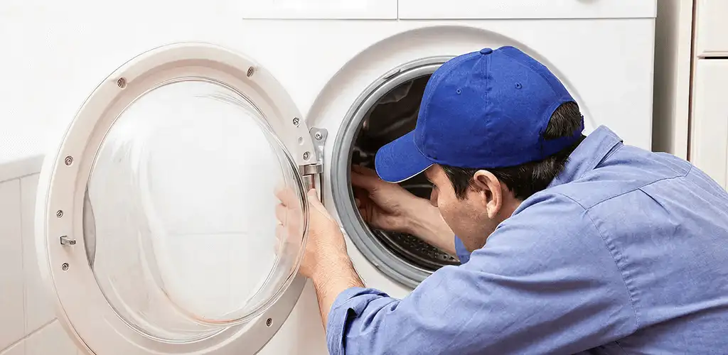 Washing machine repair handyman inspecting a front-load washer drum in Philadelphia, PA